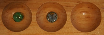 Mancala board with one stone in the first pocket and one stone in the second pocket.