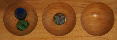 Mancala board with two stones in the first pocket and one stone in the second pocket.